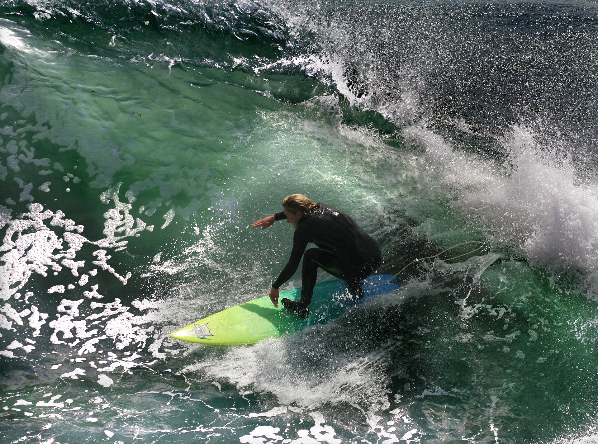 Surfer | MBolly A surfer rides a wave with spray flying around the board, showcasing exciting action.